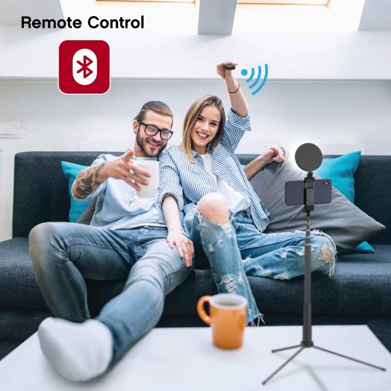 A young couple cuddling on their couch and using the included shutter remote to take a selfie with the On Air Halo Stick.
