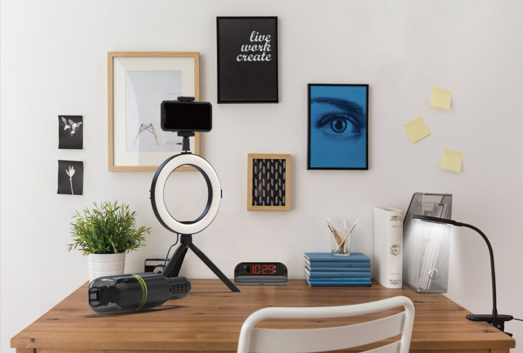 An ON AIR Ring Light, ionvac, and Atmospheres Task Lamp sitting on a desk in a college student’s dorm room.